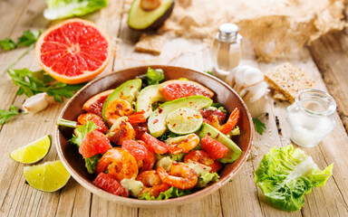 Festive shrimp salad with avocado and grapefruit on wooden background. Perfect for holiday meals and healthy celebrations