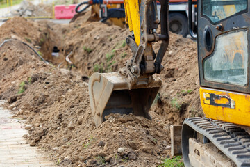 A yellow and black construction vehicle is digging a trench