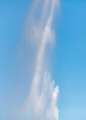 Water splashes from a fountain against a blue sky