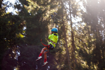 A boy bungee-sliding in the trees in summer