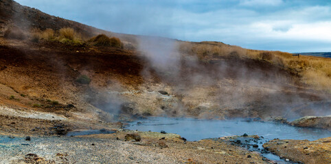 A steamy, rocky landscape with a small body of thermal waters