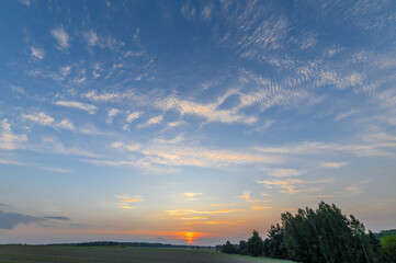 Piękna postrzępiona struktura lekkich białych chmur rozpalona promieniami zachodzącego za horyzont słońca,  © Paweł Kacperek