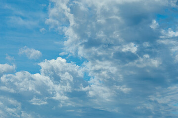 The image depicts a serene and expansive sky filled with a variety of fluffy, white clouds against a vibrant blue backdrop.