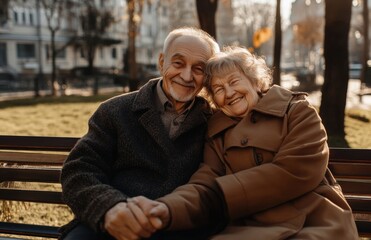 Fototapeta premium Smiling senior couple hugging on park bench in autumn, happy elderly lifestyle 
