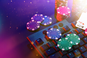 A vibrant arrangement of poker chips and playing cards on a gaming keyboard with a mouse at an online casino setup during the evening