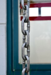 Naklejka premium Metal iron silver chain object isolated on vertical ratio outdoor building wall and window frame exterior background.