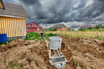 Concrete ring is installed on top of another, lowering it along roller flooring during installation of septic tank.