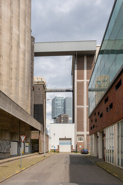 An industrial area featuring large, old-school buildings with a modern urban backdrop, showcasing a contrast between industrial design and contemporary skyscrapers in the distance in Rotterdam