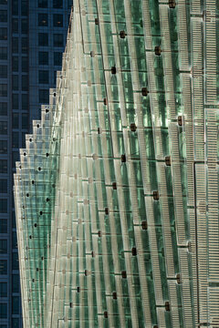 A detailed close-up of a contemporary urban building's glass panel facade, emphasizing the modern architectural design with clean lines, minimalism, and reflective surfaces.