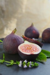 Purple figs on a black stone plate. Photo, background with fresh, juicy, ripe tropical fruits. Suitable for depicting vegetarian and raw, healthy food, harvest. Symbol of abundance and enlightenment.