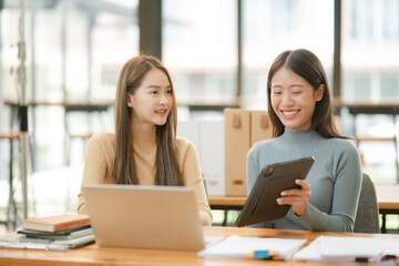 Asian businesswoman using a tapered laptop, sitting and talking in the office