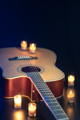 Acoustic guitar on a black background with candles.
