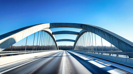 Obraz premium A modern bridge featuring curved metal structures connects two busy roads over a river on a sunny day with clear blue skies