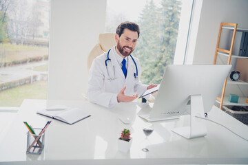 Photo of experinced doctor guy sit table having online web consultation in clinic room