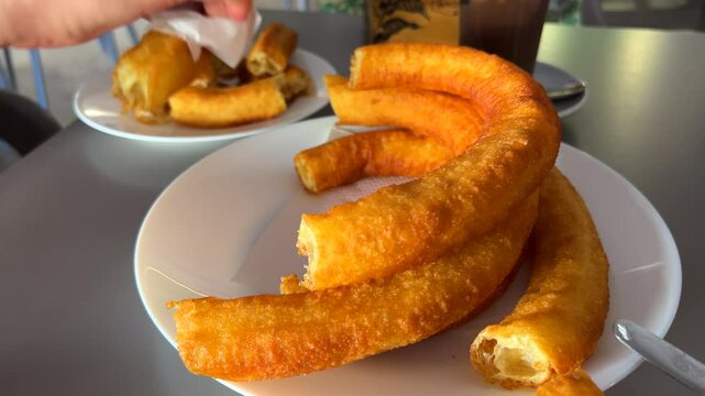 Big traditional Spanish churros porras with hot chocolate in a restaurant in Marbella Malaga Spain, delicious deep fried dough dessert, 4K shot