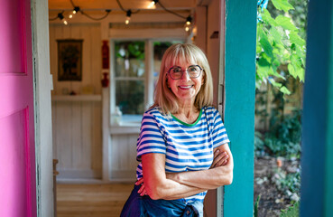 Portrait of a senior woman standing in front her wooden cottage 
