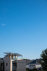 Sunny day in an urbanization of individual chalets with modern architecture. They have photovoltaic solar panels on the roofs, the sky is clear and blue. ecological and sustainable urbanism