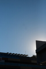 Backlit view of the roof of a modern office building with a photovoltaic solar panel installation on the community roof. Concept of an environmentally conscious society