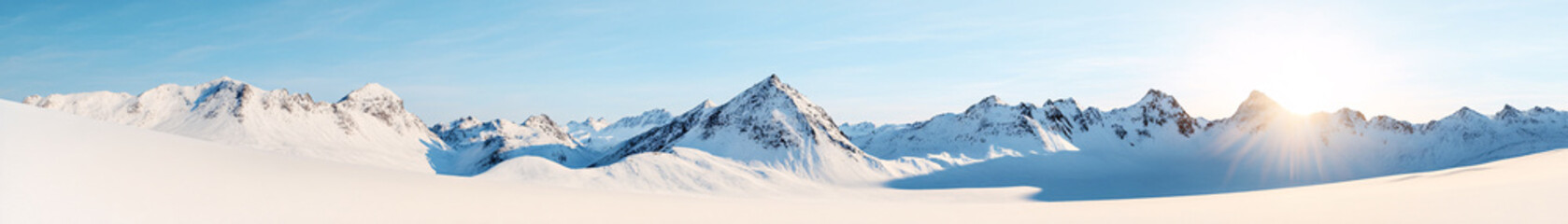 Obraz premium A sweeping panoramic view of a snow-covered mountain range, with jagged peaks piercing through the cloudless sky. The snow glistens under the midday sun, casting long shadows across the slopes. The