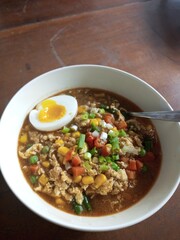  A bowl of hearty vegetable soup with colorful corn, carrots, peas, spring onions, and a soft-boiled egg. A delicious mix of spices and textures perfect for comfort food and culinary content.