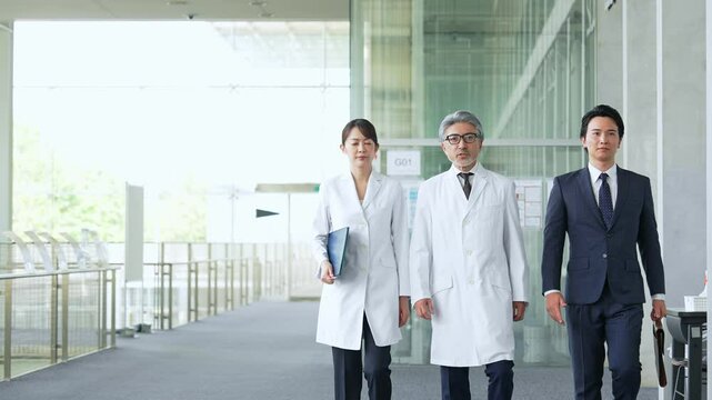 ロビーを歩くビジネスマンと白衣の医師・研究者