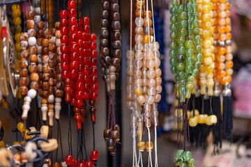 A collection of vibrant beads hangs from a market stall, each strand reflecting a unique hue and texture, inviting creativity and inspiration for jewelry making.
