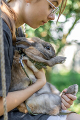 A girl plays with a domestic rabbit on the street. Pet concept.
