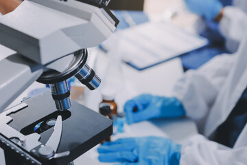 Scientist using microscope in laboratory. Close-up of a researcher's hands adjusting a modern microscope in a lab setting. Science concept