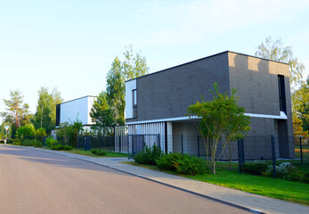 Modern luxury Villa. Street Road in Contemporary Residence. Modern Prefab house. Prefabricated home with lawn, shrubs, green courtyard in sustainable enviroment. Family House in Gated Community. Villa