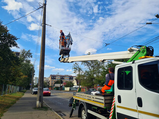 Utility services are restoring power lines. A vehicle with a lift and personnel. © dizfoto1973