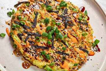 Japanese pancake with cabbage on a plate, top view