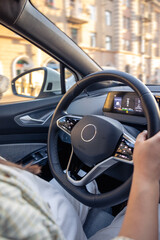 Young woman driving a car. Hands on the wheel. View from the back to the road.