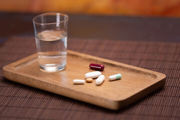 Water and medication on wooden tray for daily health routine