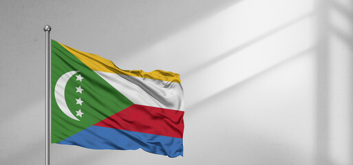 Moroni national flag cloth fabric waving on beautiful window light grey Background.