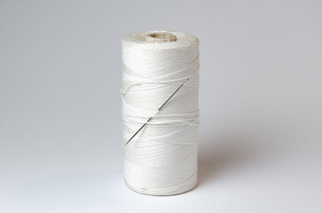 One single thread spool with needle on white background