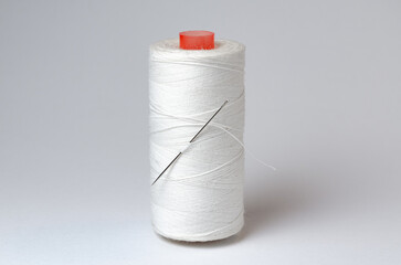 One single thread spool with needle on white background