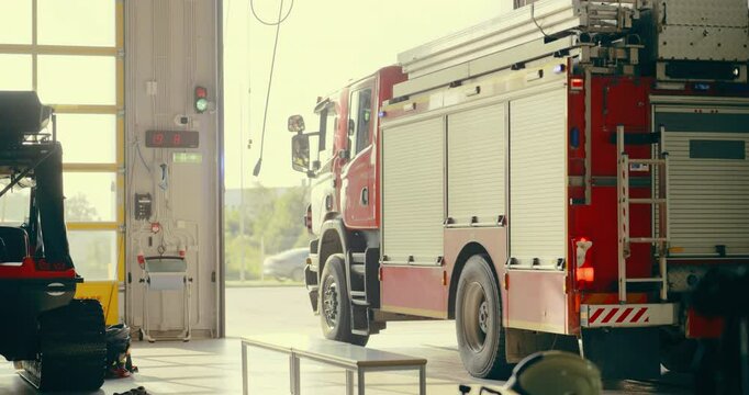 Fire Truck Moves Into Action as the Garage Door at Fire Department Opens. Vehicle with a First Response Team Pulls Out of the Station, Sirens and Lights Activated, Racing to an Emergency Call