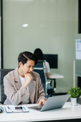 Confident Asian man with a smile standing holding notepad and tablet at office.