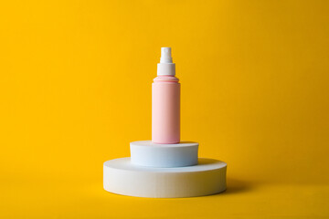 Fototapeta premium Cosmetic pink bottle, bottle, lotion or serum with stylish props on yellow background. 
