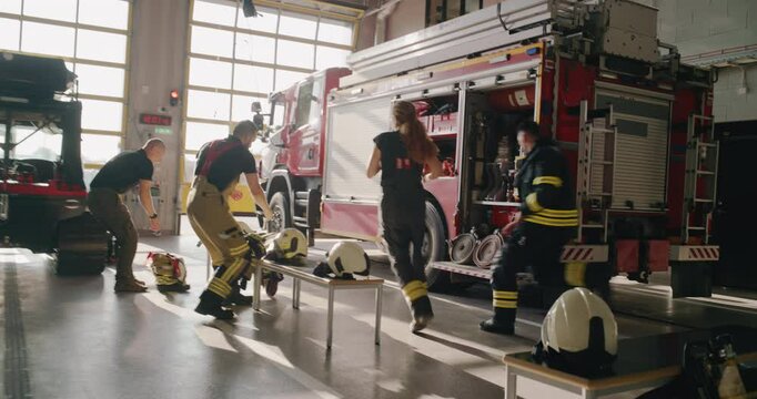 Follow Footage of a Female Running to Gear up and Board a Fire Truck Together with the Male Crew. Team of Firefighters in the Fire Station Demonstrating Urgency and Readiness for an Emergency Call