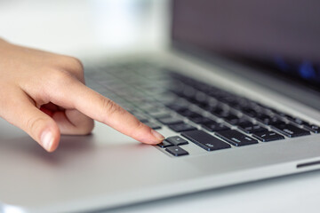 The girl is typing on the laptop keyboard. Girl's hands on the keyboard.