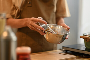 Young man wearing apron preparing spaghetti bolognese at kitchen counter
