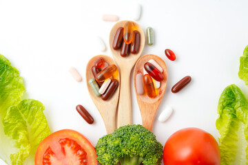 Colorful pills and capsules in wooden spoon with fresh vegetables, Vitamins and supplement
