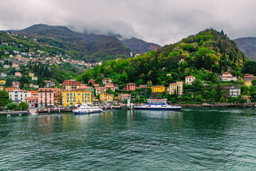 Fototapeta premium Ferry arrives at famous Italian tourist destination lakeside Varenna on Como lake, Aerial