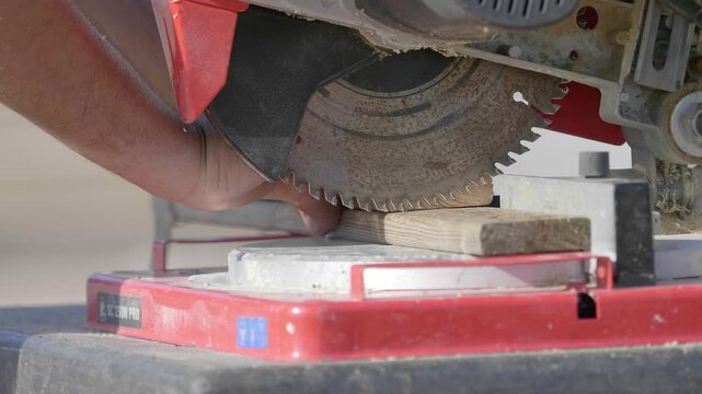 A table saw is actively cutting through a wooden board, showcasing the precision and power of the tool in a workshop setting.