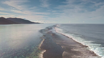 Aerial drone flight over shallow coral barrier reef tropical island coast with crystal clear water and waves breaking calm surface. Natural beauty relaxation landscape. Wild nature travel background