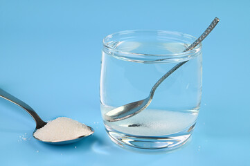 Sugar water in a glass cup. Adding sugar crystals in a glass of water.