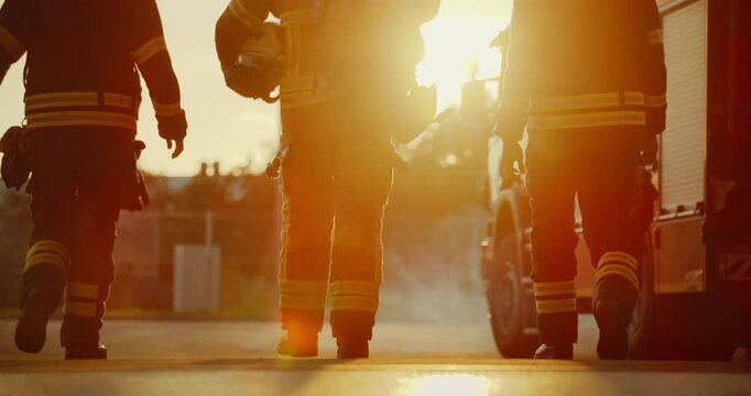Diverse Team of Firefighters in Full Gear Walking Towards a Fire Truck at Sunset, Ready for Action. Scene Captures Their Unity, Bravery and Dedication to Saving Lives in Emergencies