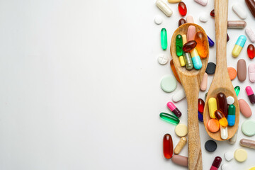 Group of varied pills Vitamin capsules in a wooden spoon, soft gels, Fish oil capsules, tablets...