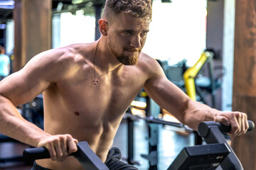 Naklejka premium Athlete doing exercises on an air bike exercise bike close-up.